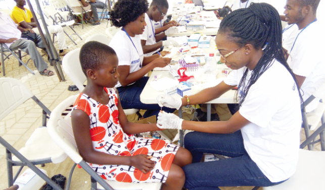 A health professional attending to a young girl while other health workers are engaged in documentation A health professional attending to a young girl while other health workers are engaged in documentation